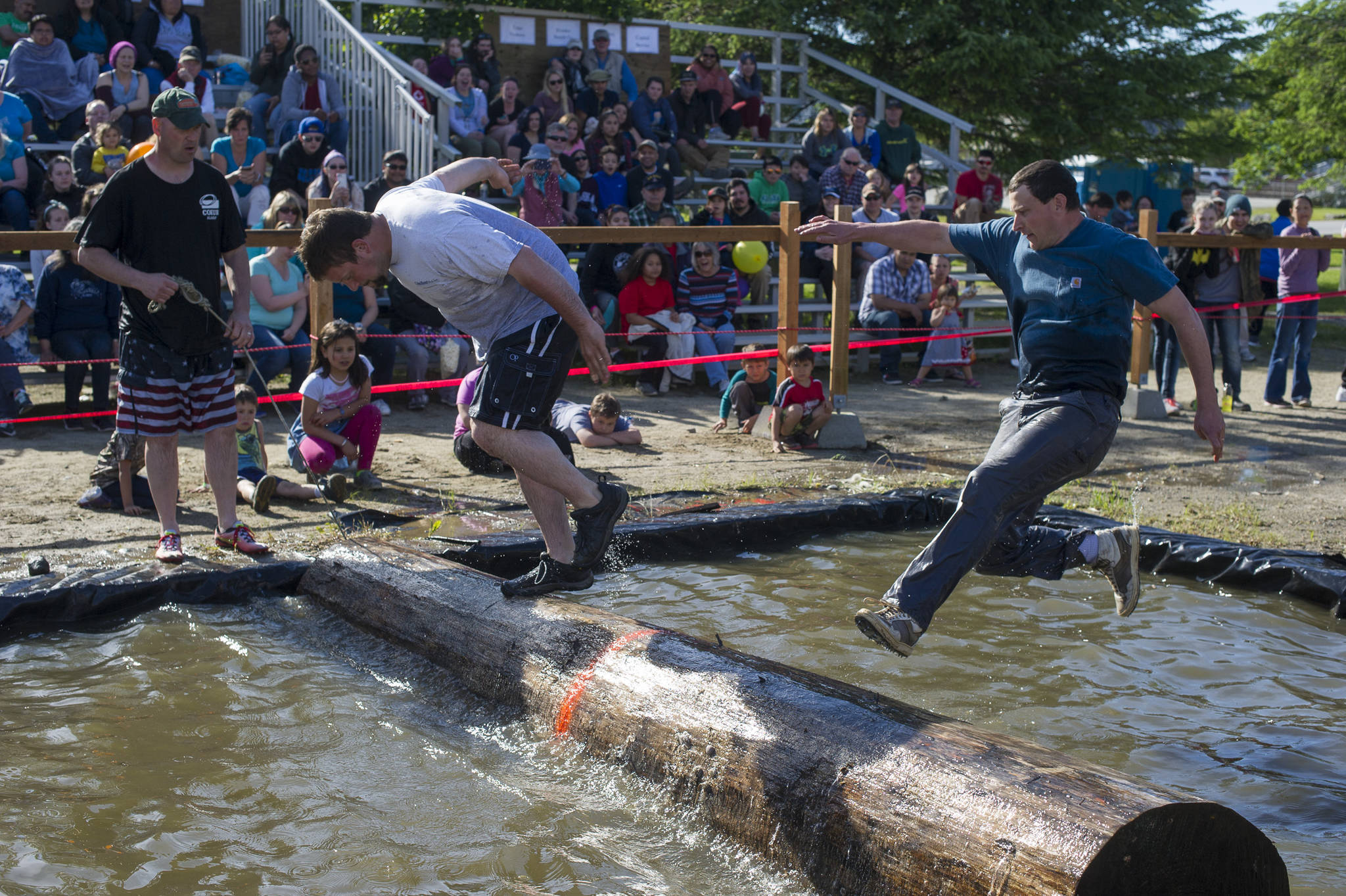 Jessie Ross, right, loses his balance against Ryan Friend in the log rolling contest at the 27th Annual Gold Rush Days Competition at Savikko Park on Sunday, June 18, 2017. (Michael Penn | Juneau Empire File)