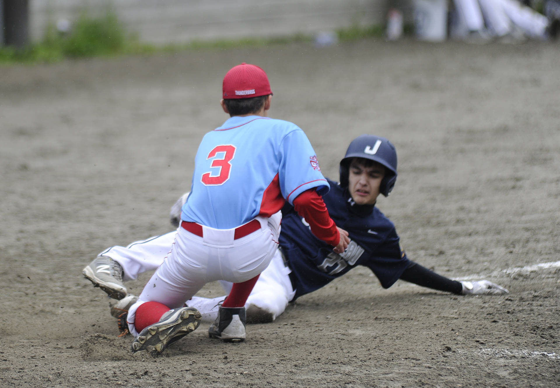 East Post 34 pitcher Ian Carle applies a tag on Juneau Post 25 outfielder Brennon Ludeman in the fifth inning at Adair-Kennedy Memorial Field on Saturday. Ludeman was safe on the play and Juneau won the game moments later on another play at home plate. (Nolin Ainsworth | Juneau Empire)