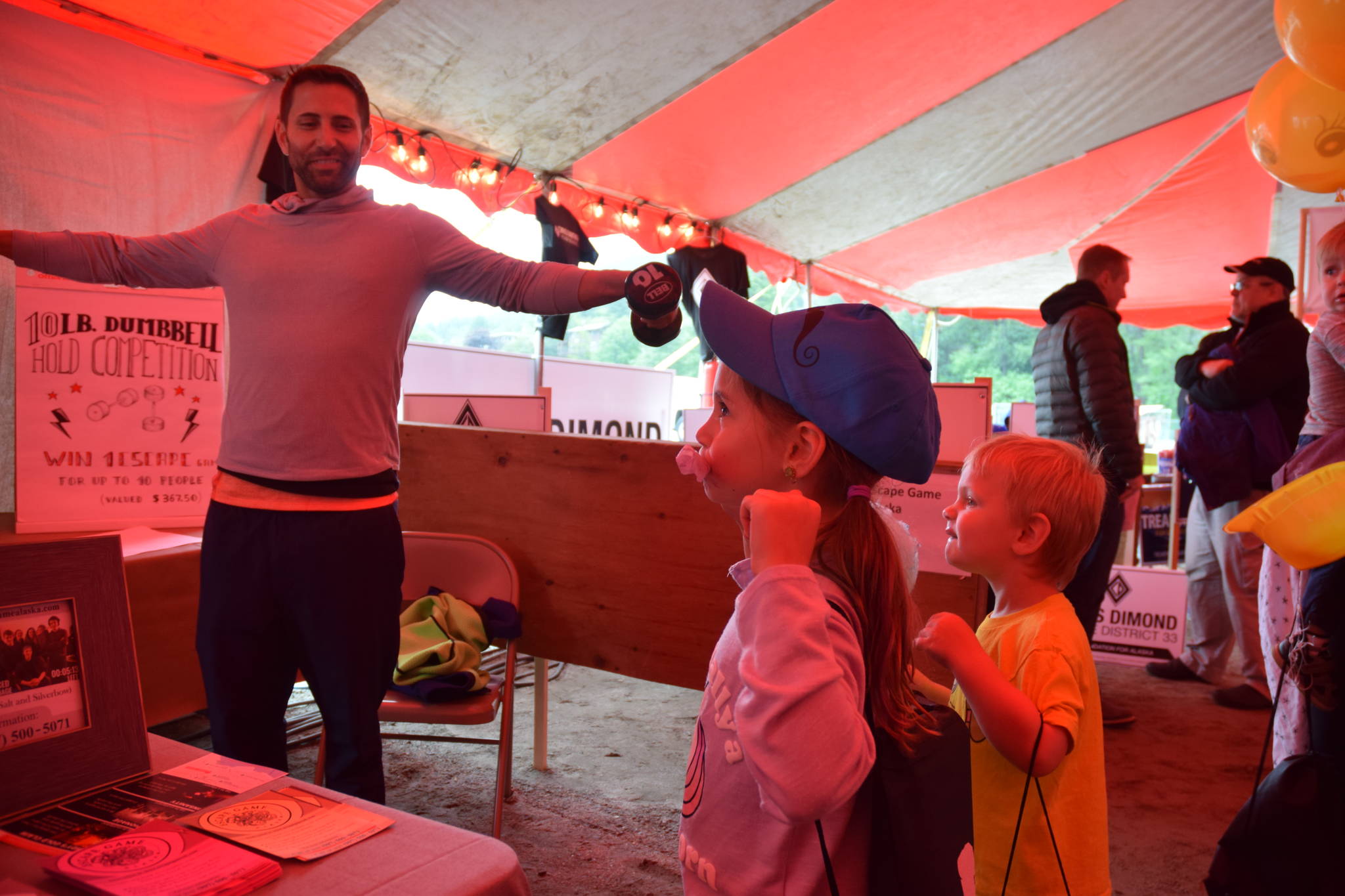Jared Lee tries to impress his children, Sienna and Lennox, by holding 10-pound dumbbells as long as he can as part of a competition. (Kevin Gullufsen | Juneau Empire)