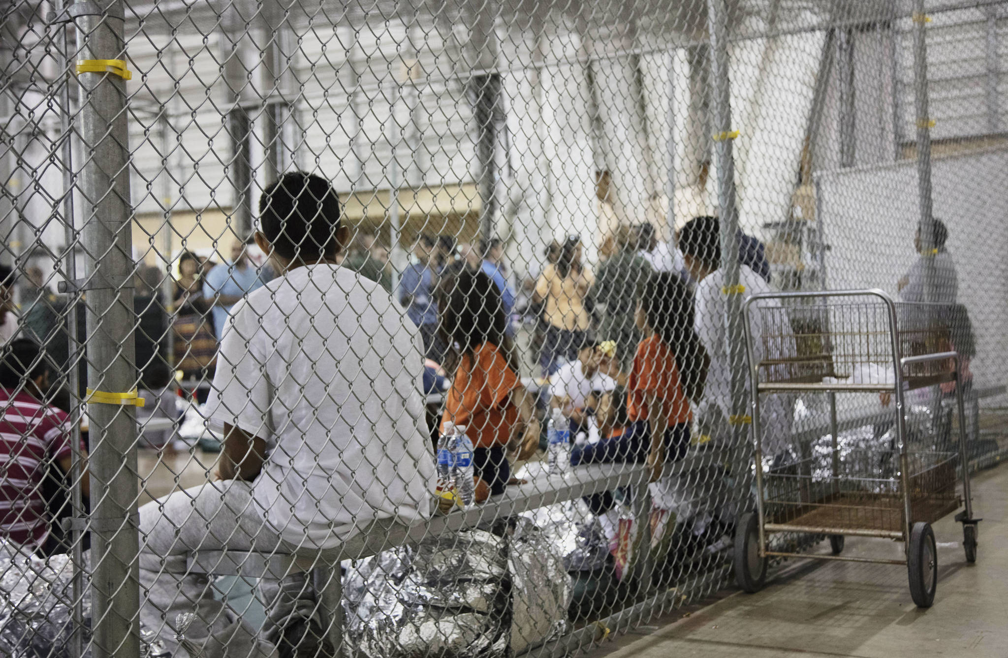 In this photo provided by U.S. Customs and Border Protection, people who’ve been taken into custody related to cases of illegal entry into the United States, sit in one of the cages at a facility in McAllen, Texas, Sunday, June 17, 2018. (U.S. Customs and Border Protection’s Rio Grande Valley Sector via AP)