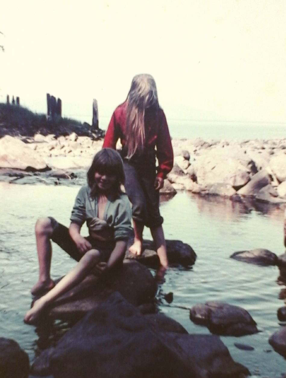 Megan Neilson (front) and author Tara Neilson playing in the cannery creek with the burned pilings in the background.