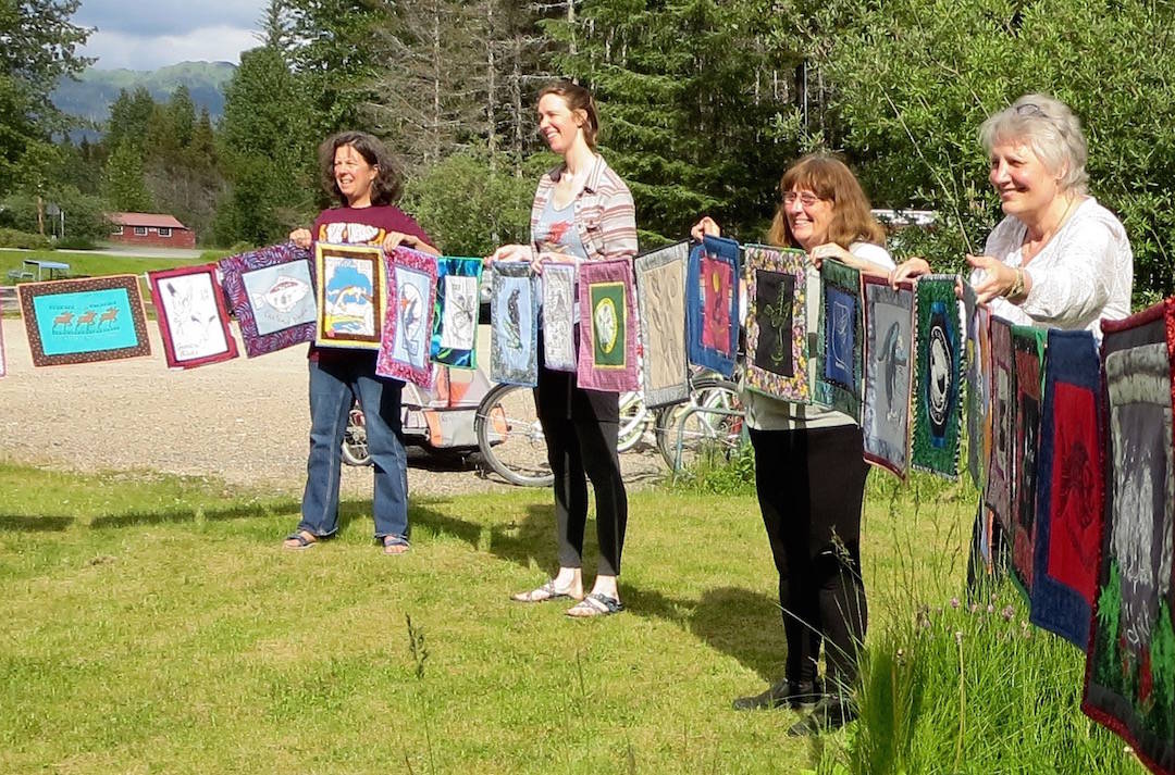 Chris Gabriele, Rebekah Wierda, Annie Mackovjak and Becky King hold some of the quilts on a string in Gustavus. Photo courtesy of Ellie Sharman.