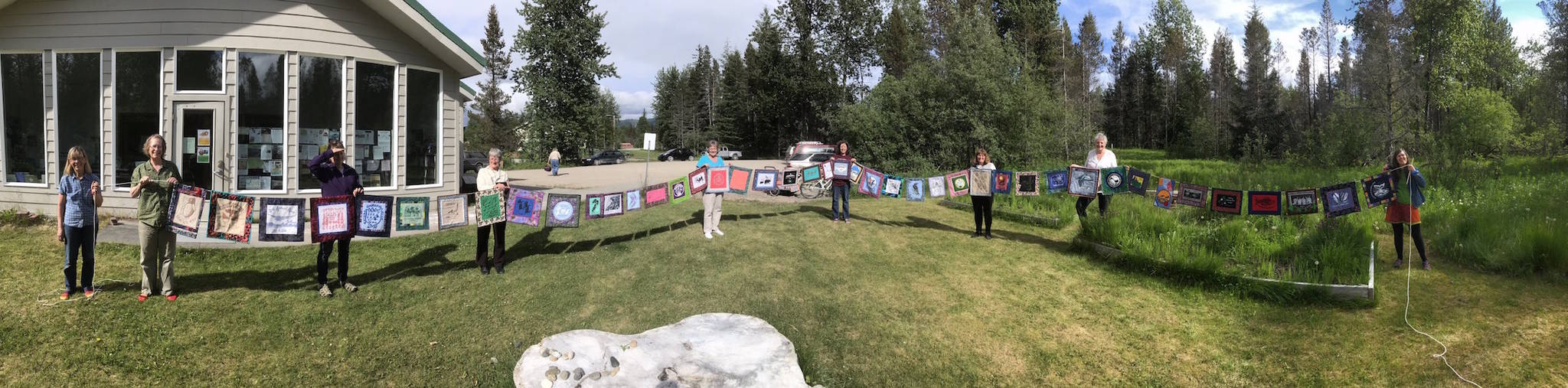From left to right: Meadow Brook, Kate Boesser, Denise Pratschner, Sandy Schroth, Rita Savage, Chris Gabriele, Annie Mackovjak, Becky King and Ellie Sharman hold up all of the”quiltlets” together, running about 85 feet long. Photo courtesy of Ellie Sharman.