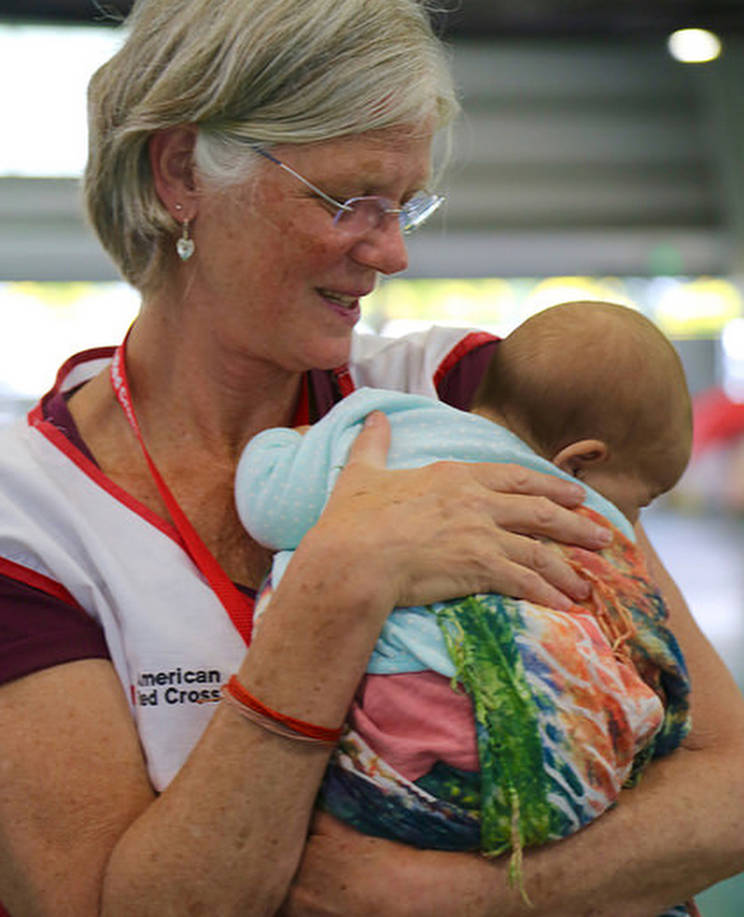 Red Cross Mental Health Service Associate Annie Caulfield, a Juneau resident, holds a baby while deployed in Hawaii in May 2018. Caulfield and other volunteers were there in response to the Kilauea Volcano eruption that has displaced thousands of people. (American Red Cross | Courtesy Photo)