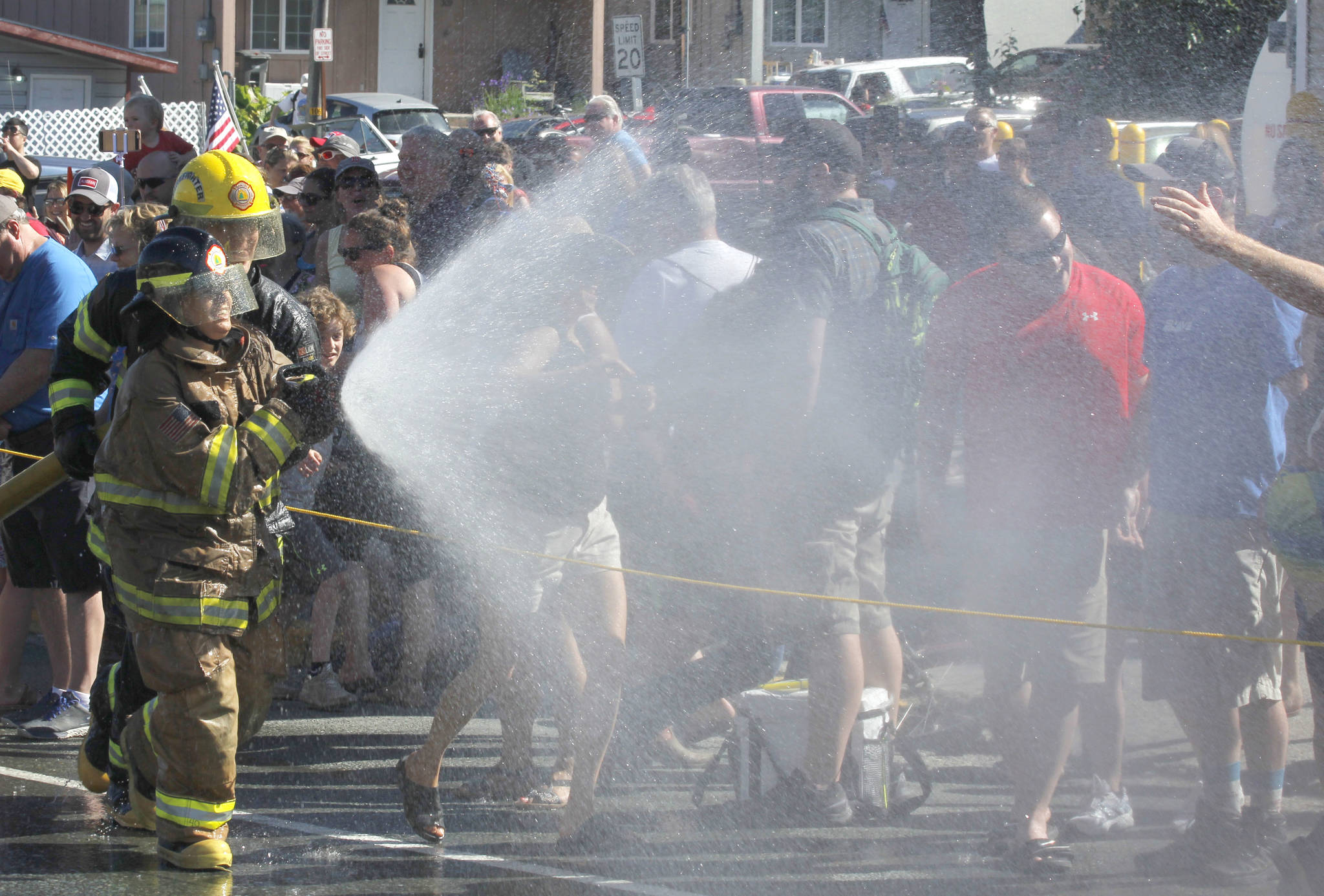 Firefighter Emily Lockie sprays down the crowd at the annual Make & Break hose race in Douglas on Wednesday, July 4, 2018. (Alex McCarthy | Juneau Empire)
