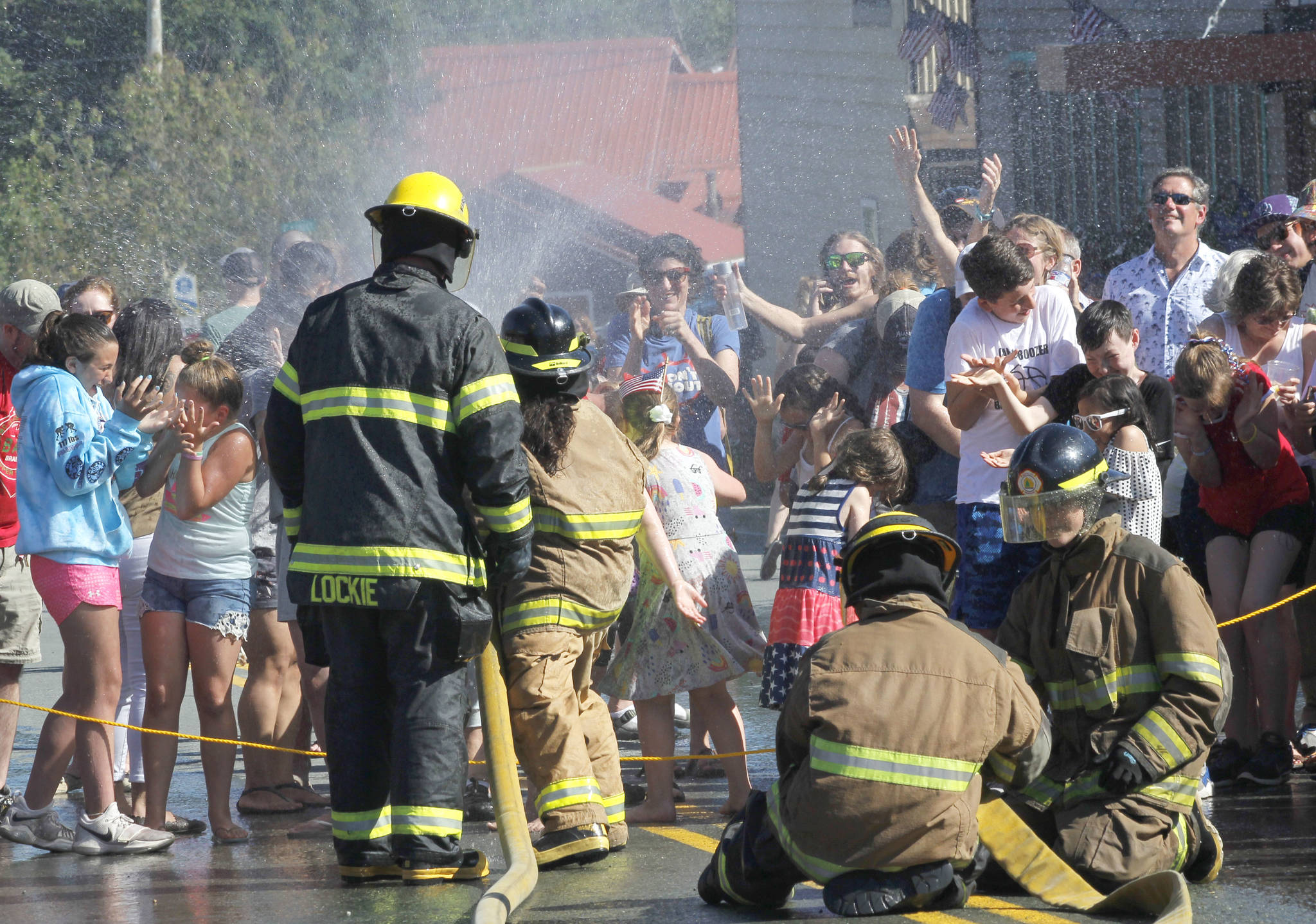 Spectators react as Firefighter Emily Lockie sprays down the crowd at the annual Make & Break hose race in Douglas on Wednesday, July 4, 2018. (Alex McCarthy | Juneau Empire)
