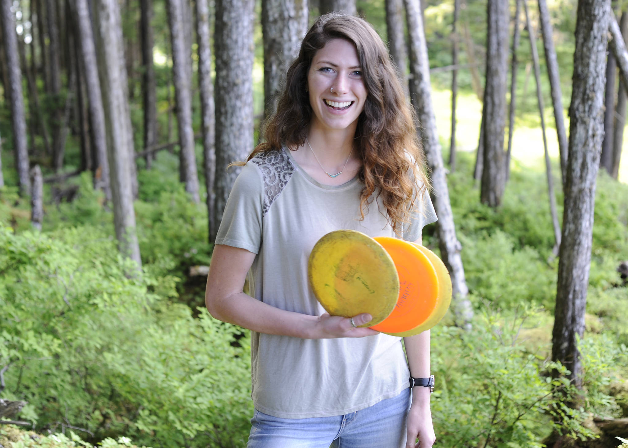 Morgan Johnson, 21, stands in the woods behind John Pugh Hall on the campus of the University of Alaska Southeast, the site of future disc golf course she is building. (Nolin Ainsworth | Juneau Empire)
