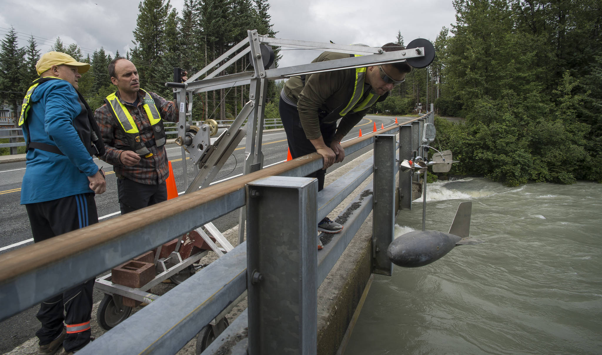 Randy Host, Jamie Pierce and Rob Schenker of the United States Geological Survey prepare to take water volume measurements of the Mendenhall River off the Mendenhall Loop Road Bridge on Thursday, July 19, 2018, after a release of water from Suicide Basin on Wednesday. (Michael Penn | Juneau Empire)