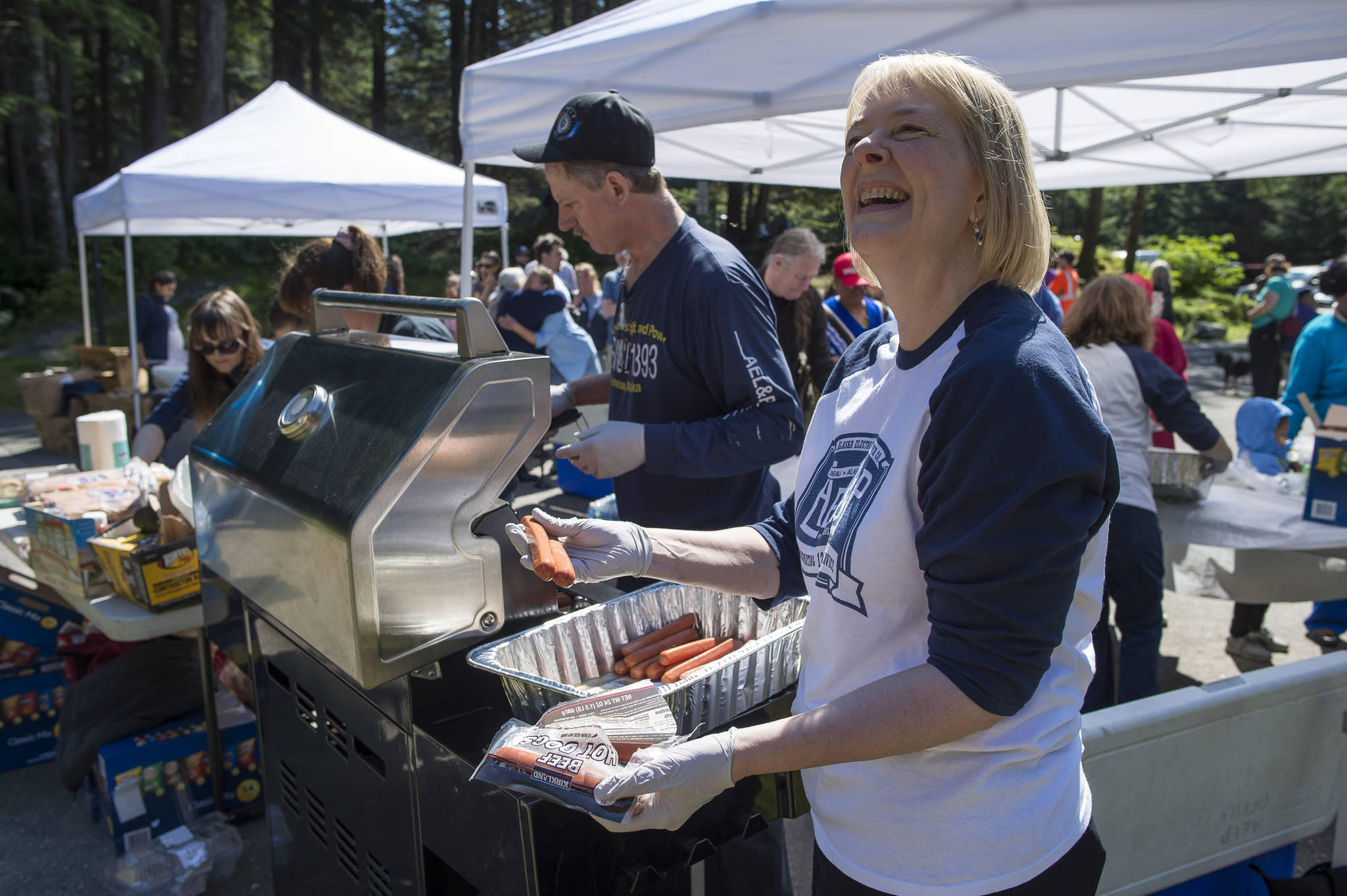 Connie Hulbert, President and General Manager of AEL&P, helps prepare food as the company celebrate its 125th year in business with a public picnic at Cope Park on Friday, July 20, 2018. The public was also invited to tour the Gold Creek Power Plant. (Michael Penn | Juneau Empire)
