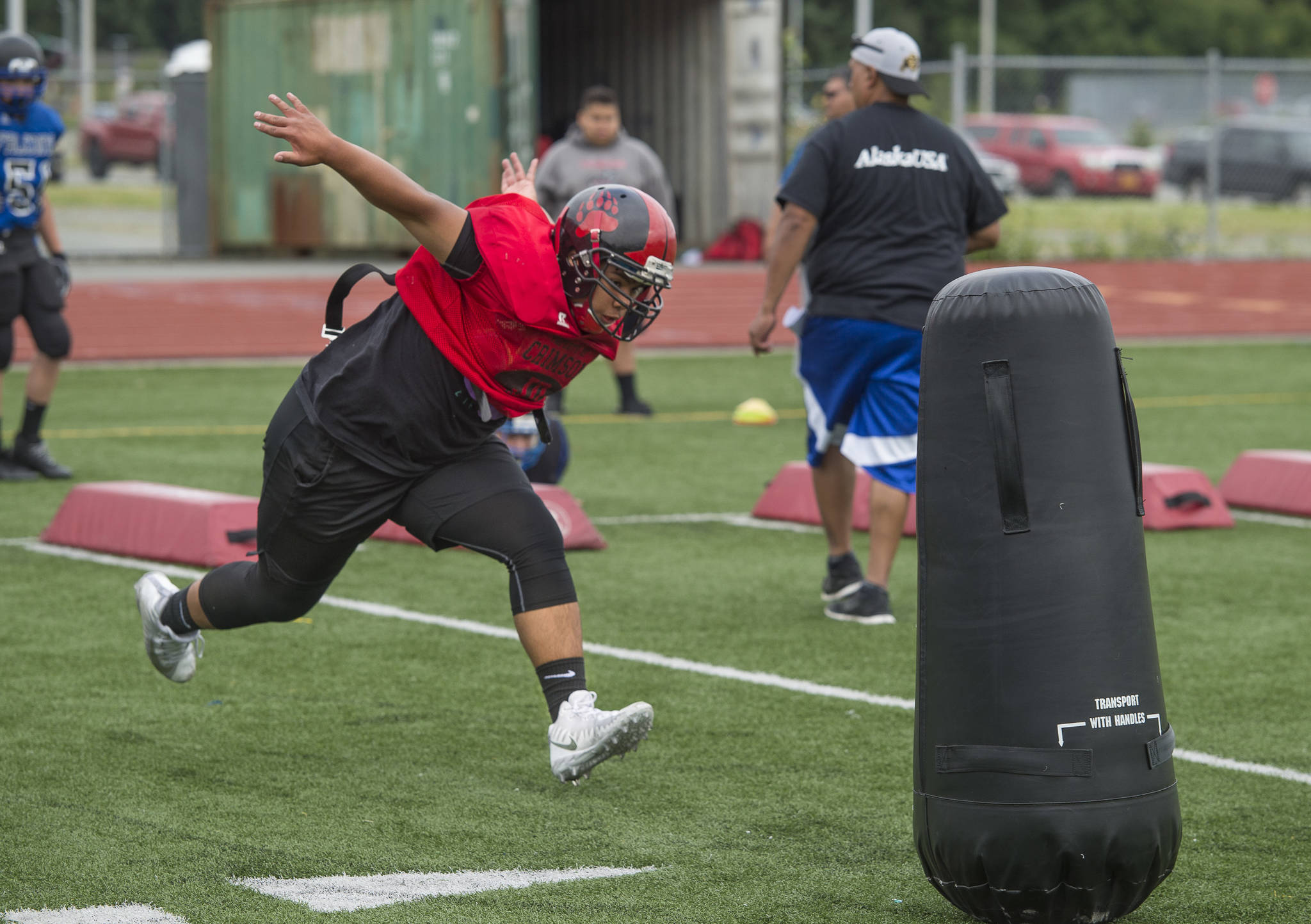 Marcos Yadao, of Juneau-Douglas High School, works on a footwork and tackling drill run by his father, Vince, during Juneau Football practice at Thunder Mountain High School on Thursday, July 26, 2018. (Michael Penn | Juneau Empire)
