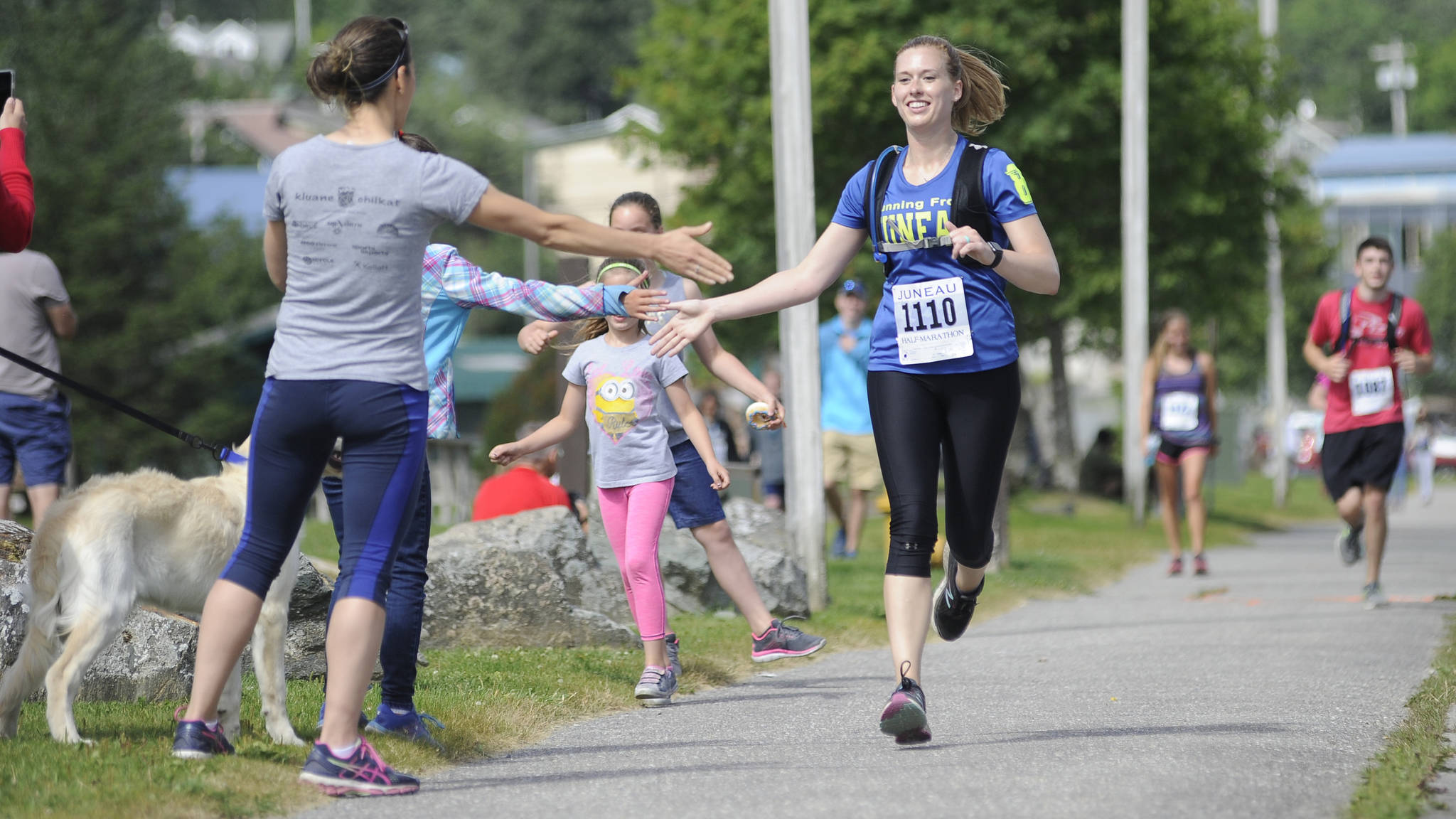Nicole Gorle, 27, high fives a spectator while finishing the Juneau Half Marathon on Saturday at Savikko Park. (Nolin Ainsworth | Juneau Empire)