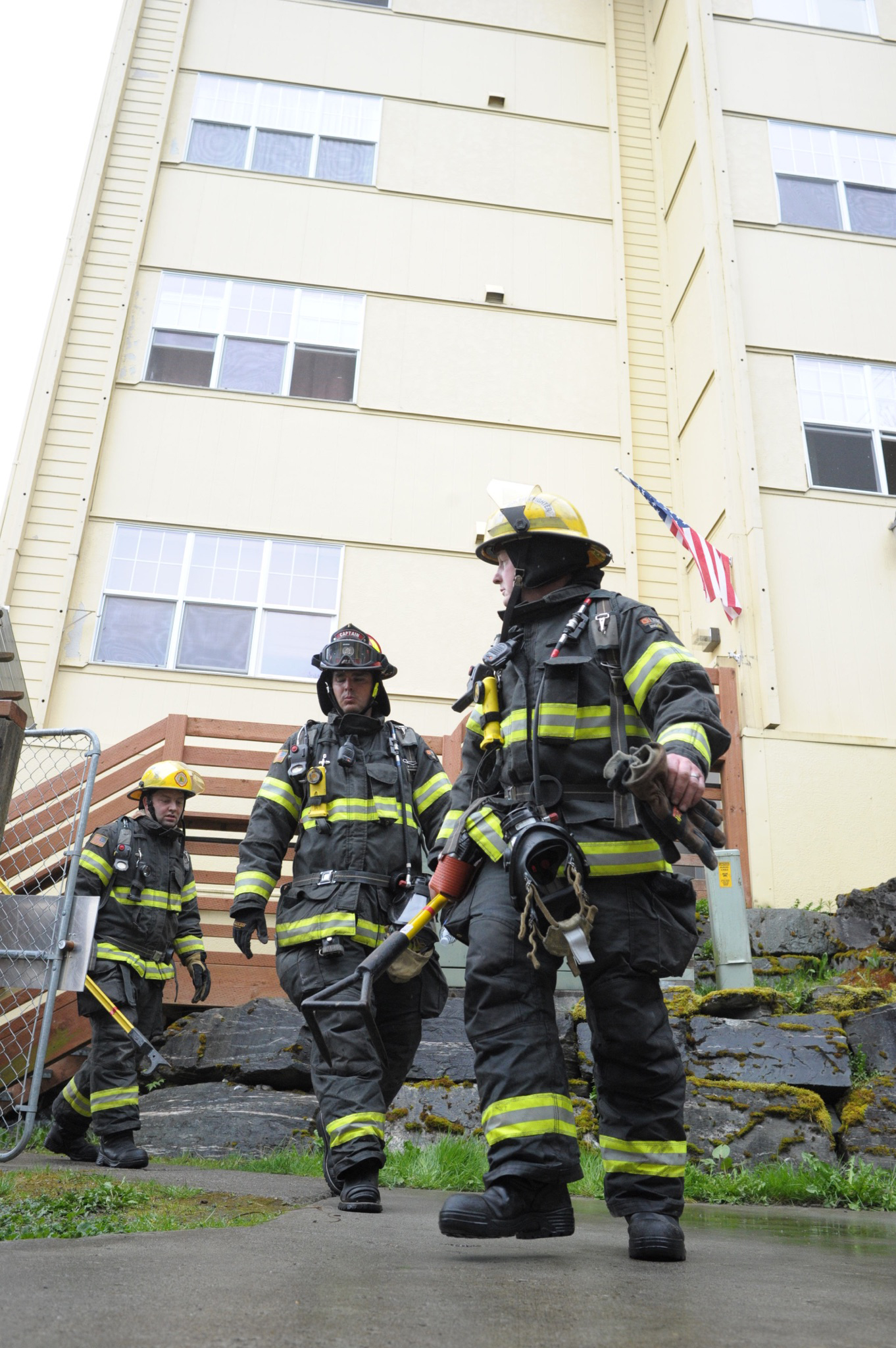Firefighters leave the Channel View Apartments Sunday after clearing the building in response to a fire on the building's fifth floor.