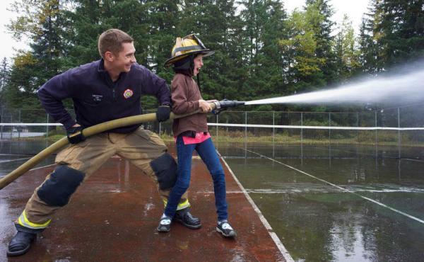 Capital City Fire & Rescue Firefighter Sean Rhea helps Floyd Dryden Middle School seventh grader Kimberly Clark operate a fire hose as part of her Science Technology Engineering and Math (STEM) class.
