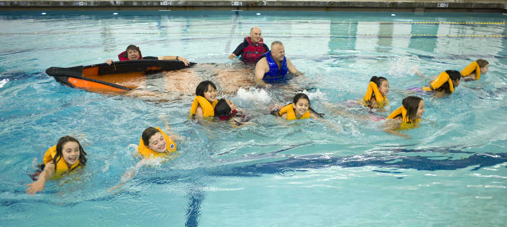Third grade girls from Harborview Elementary School swim from a sinking boat as they learn water safety at the Augustus Brown Public Swimming Pool on Friday. Helping teach are Coast Guard Auxiliary members Mark Hunt, left, and Stu Robards, center, and current Coast Guard Chief Chief Warrant Officer Rick Nieves.