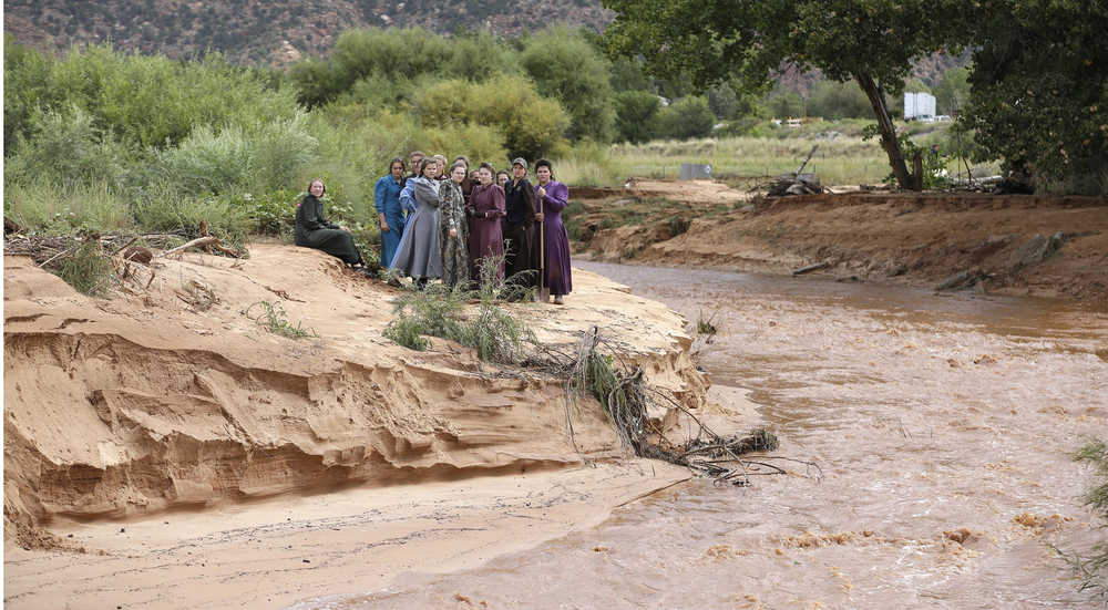 In this Sept. 15 photo, community members look along a stream after a flash flood in Colorado City, Arizona.