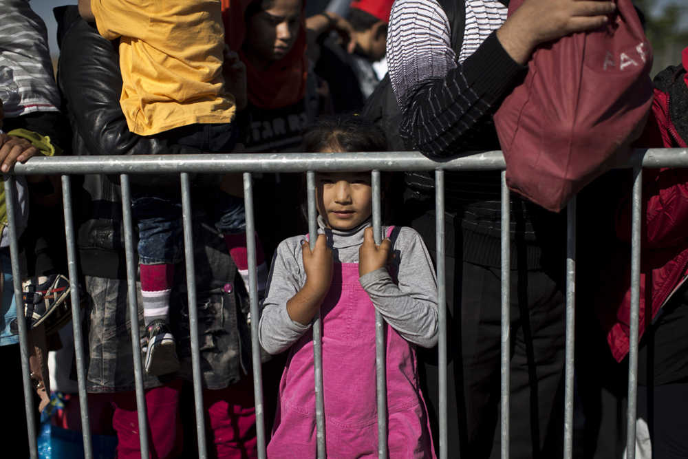 A girl stands behind a barrier as people queue to get into a reception center for migrants and refugees in Opatovac, Croatia, Wednesday.