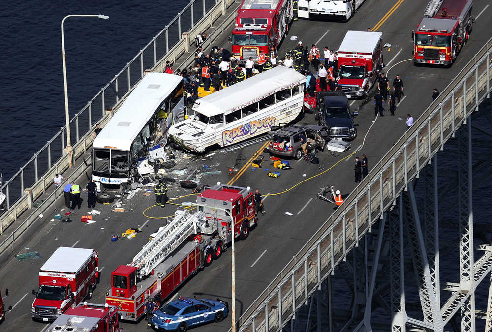 Emergency personnel work at the scene of a fatal collision involving a charter bus, center left, and a "Ride the Ducks" amphibious tour bus on the Aurora Bridge in Seattle on Thursday, Sept. 24, 2015. (Ken Lambert/The Seattle Times via AP)  SEATTLE OUT; USA TODAY OUT; MAGAZINES OUT; NO SALES; TELEVISION OUT; MANDATORY CREDIT: KEN LAMBERT/THE SEATTLE TIMES