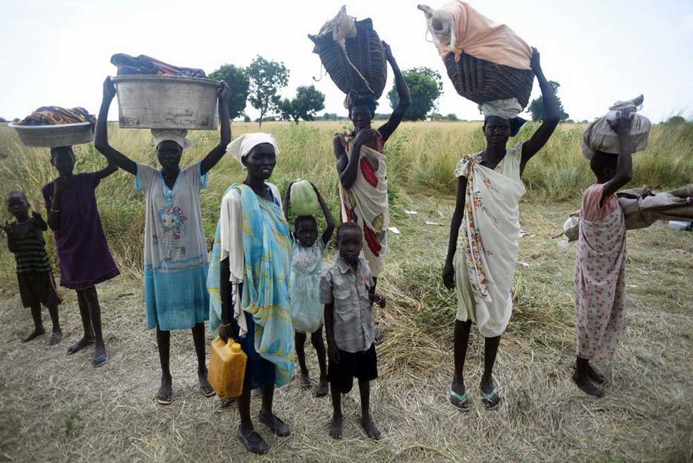 Women stand with their children and belongings in rebel held Bauw village in Koch county of South Sudan's Unity state on Friday.