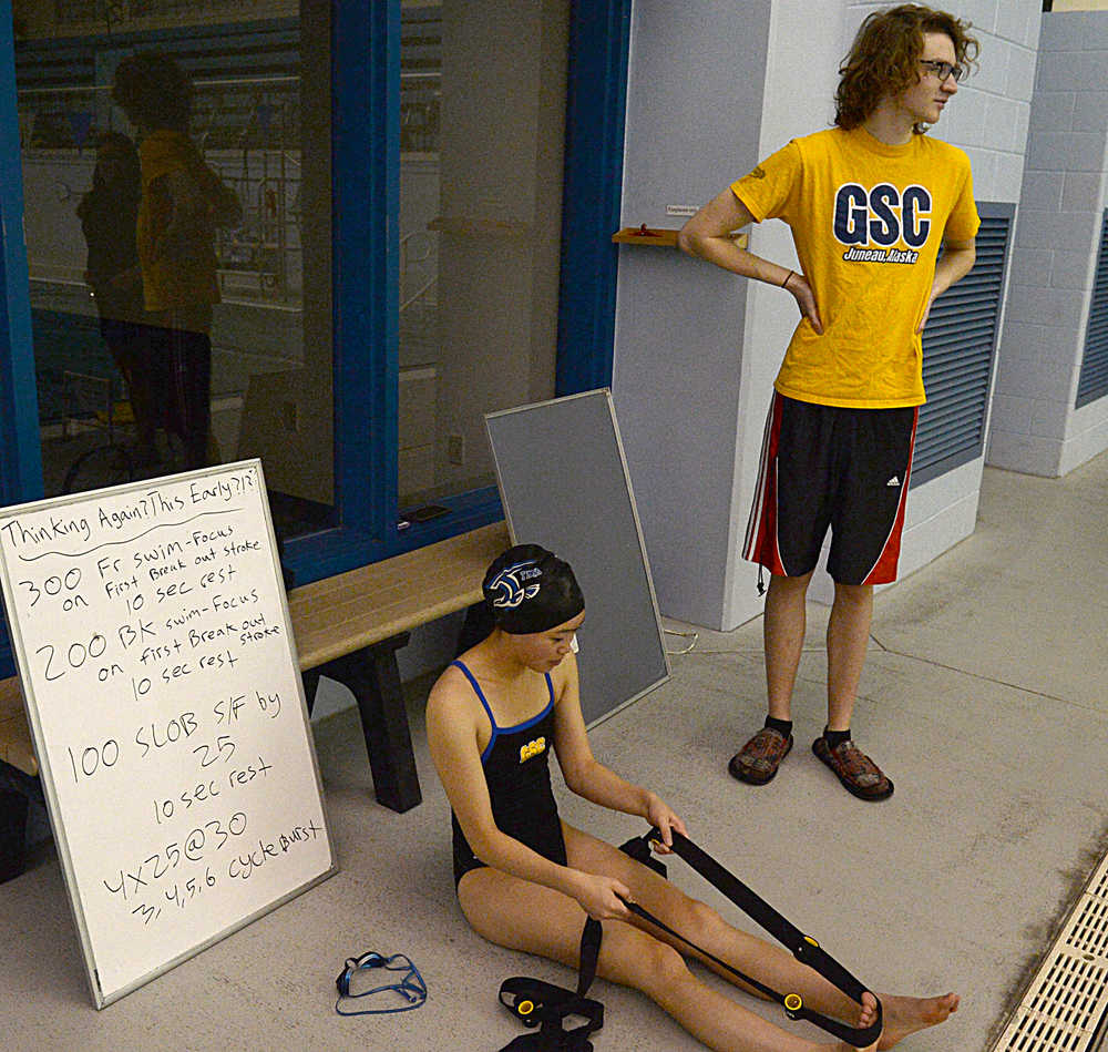 Thunder Mountain High school sophomore Annie Hagen stretches as assistant coach Josiah Loseby looks on during a recent Falcons practice. TMHS and Juneau-Douglas will host a Southeast schools swim meet on Friday and Saturday at the Dimond Park Aquatics Center.