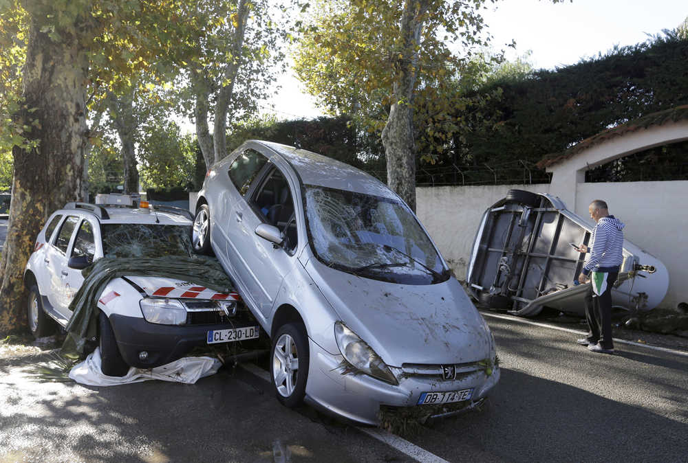 A man walks past damaged cars in Biot, near Cannes, France on Sunday. Sudden heavy rains around the French Riviera have killed at least 10 people, including some trapped in cars, a campsite and a retirement home, and left six missing.