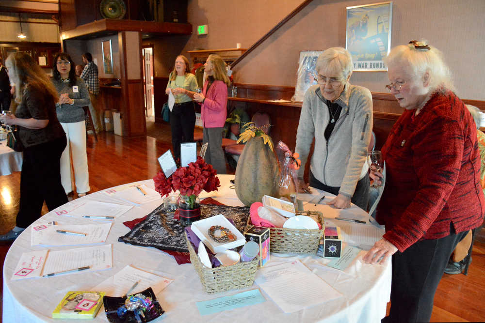 League of Women Voters of Juneau members Pat Watt, left, and Judy Andree, right, check out the silent auction items in the Hangar Ballroom.