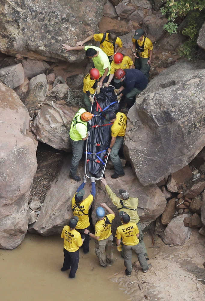 FILE - In this Sept. 16, 2015 file photo, search and rescue team members carry a body after it was found along Pine Creek, in Zion National Park, near Springdale, Utah.  Zion National Park officials are retracing what led up to the deaths of seven people in a flooded canyon on Sept. 15 before a panel assesses what can be done to keep a growing number of visitors safe when spectacular natural settings turn perilous. (AP Photo/Rick Bowmer, File)