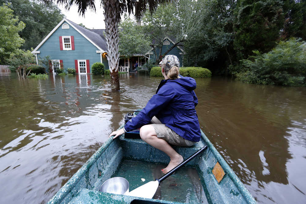 Jeanni Adame rides in her boat as she checks on neighbors Tara Saracina seeing if she wants to evacuate  in the Ashborough subdivision near Summerville, S.C., after many of their neighbors left Monday, Oct. 5, 2015. South Carolina is still struggling with flood waters due to a slow moving storm system. (AP Photo/Mic Smith)