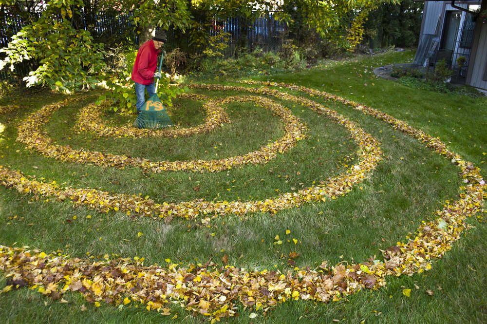 Juneau artist Jay Crondahl adds a little ephemeral art to the lawn at the Park Shore Condominiums on Monday.