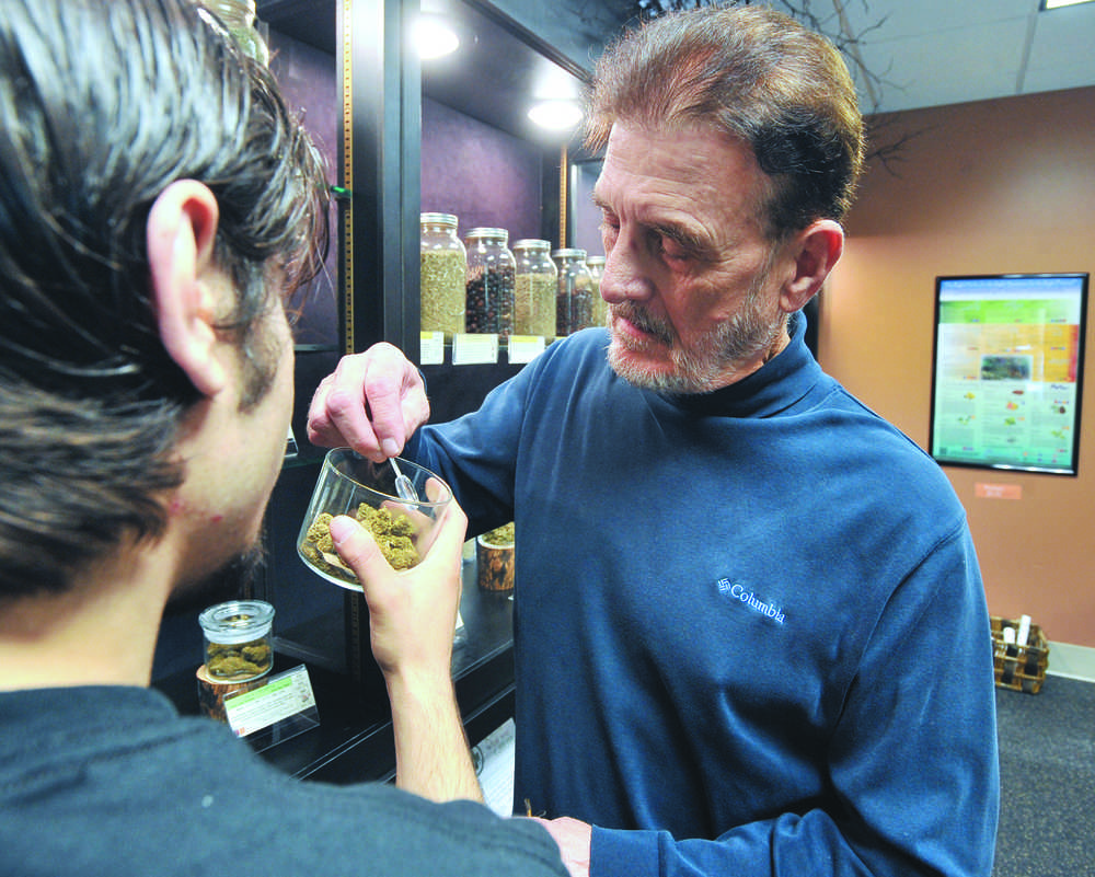 Theodore Alex Bastia, Jr. examines pot before making a purchase at Breeze Botanicals, Thursday, Oct. 1, 2015, in Ashland, Ore. Oregon marijuana shops began selling marijuana Thursday for the first time to recreational users, marking a big day for the budding pot industry.  (Jamie Lusch/The Medford Mail Tribune via AP) MANDATORY CREDIT