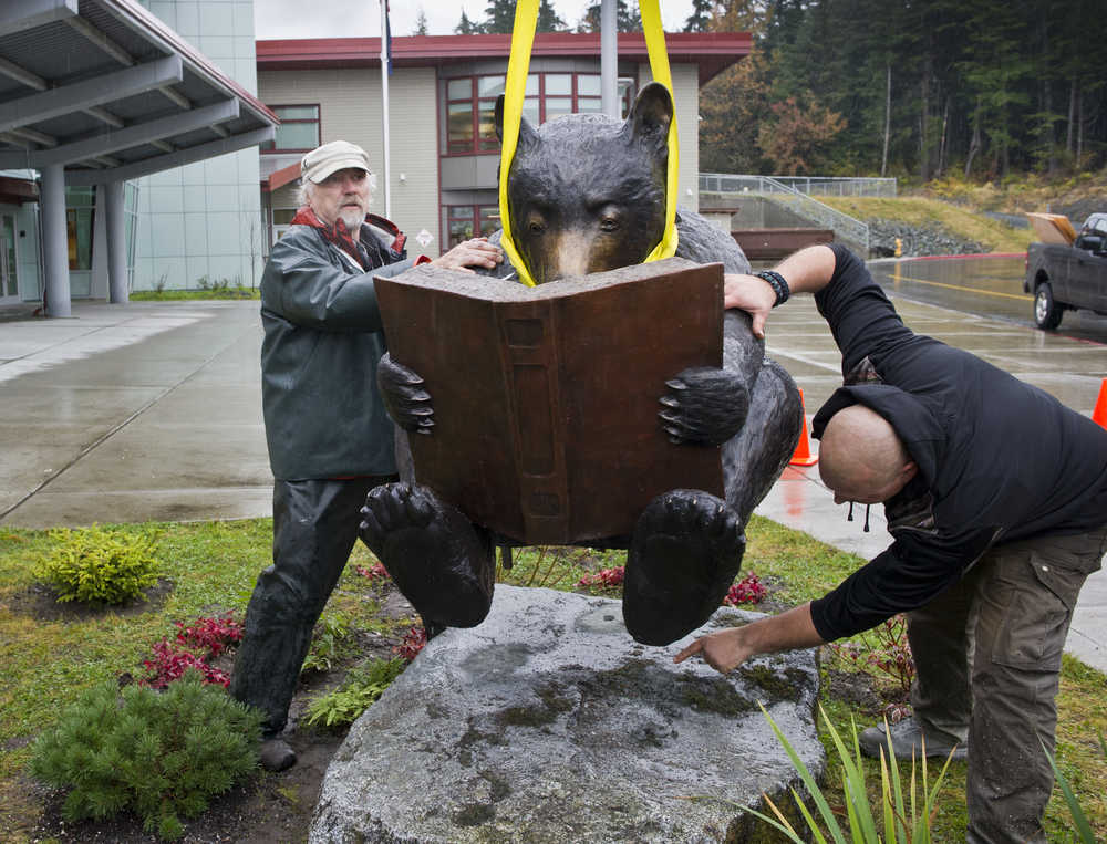 Juneau artist Dan DeRoux, left, works with John Salyers to install his bronze bear sculpture in front of the Auke Bay Elementary School on Thursday.