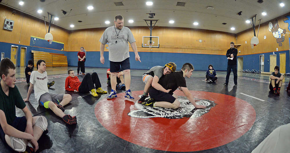 Region V wrestling official Matt Ferster conducts an instructional tutorial with Juneau-Douglas High School juniors Ethan Goebell and Cody Weldon at a recent Crimson Bears practice. The duo, along with senior Taylor Sutac, are the team's co-captains this season.