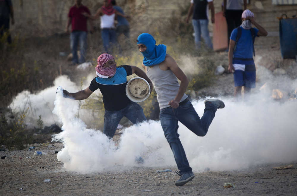 A Palestinian protester throws back a tear gas canister that was fired by Israeli troops during clashes near Ramallah, West Bank, Thursday, Oct. 15, 2015. In the current wave of violence, eight Israelis have been killed in stabbing and shooting attacks, as of Thursday. Thirty-one Palestinians have been killed, including 14 identified by Israel as attackers, and the others in clashes between stone-throwers and Israeli troops. (AP Photo/Majdi Mohammed)