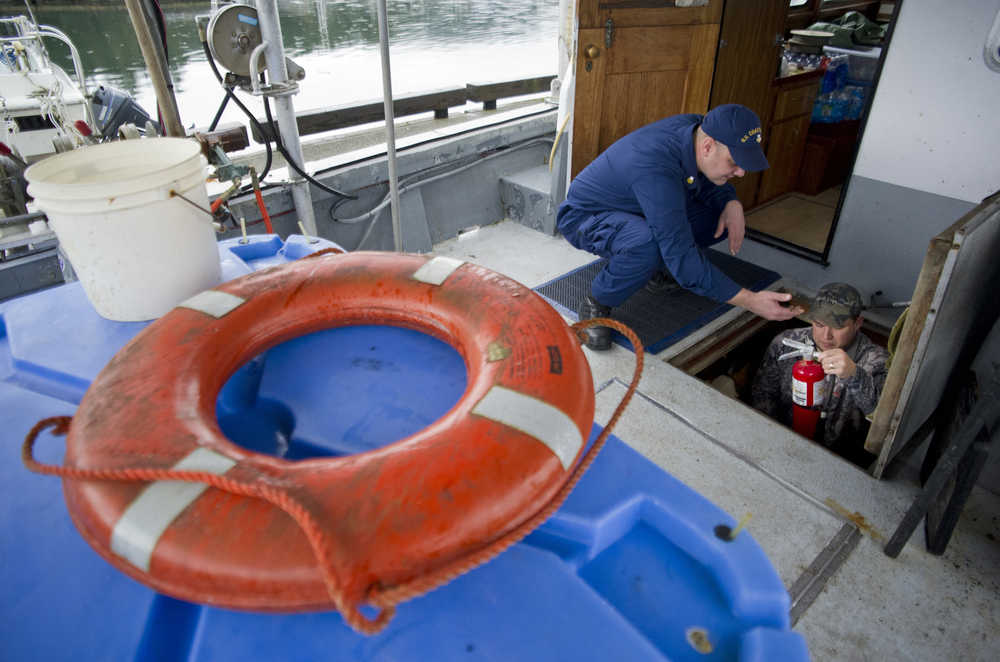 Jacob Miller shows U.S. Coast Guard First Class Ben Stixrud his safety gear on his 41-foot power troller at the Don Statter Memorial Boat Harbor in Auke Bay on Friday.
