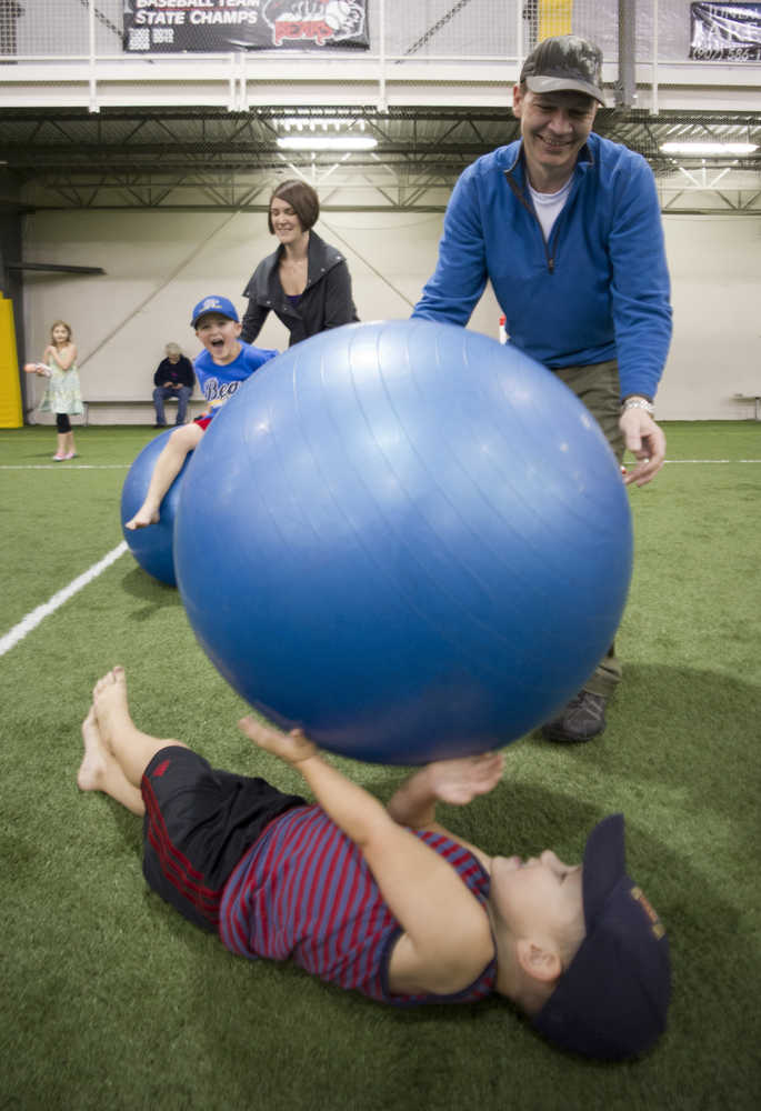 Steve Carlton and his wife, Heather, play with their children, Theo, 3, below, and Arlo, 5, during the Moon Walk for Alaska Day at the Dimond Park Fieldhouse on Monday.