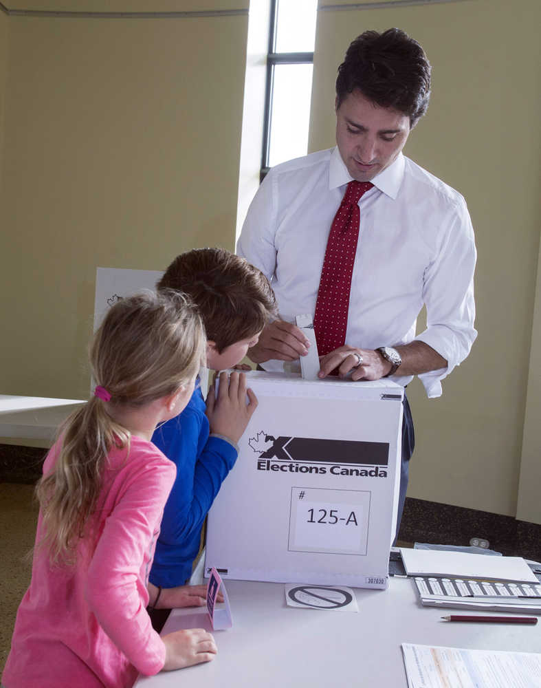 Liberal leader Justin Trudeau drops his vote in the ballot box as his daughter Ella-Grace, left, and son Xavier look on Monday in Montreal.