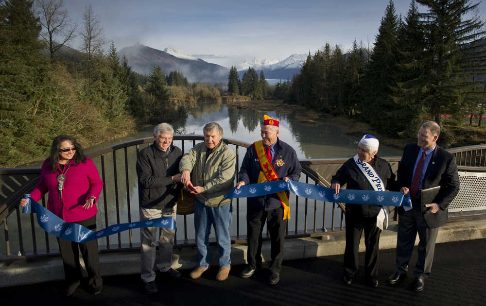 Lt. Gov. Byron Mallott, second from left, helps Roy Peratrovich, Jr., cut a ribbon as Sandra Garcia-Aline, of the Federal Highway Administration, left, Sasha Soboleff, Grand President of the Alaska Native Brotherhood, Johanna Dybdahl, Grand President  of the Alaska Native Sisterhood, and Marc Luiken, Commissioner of the Alaska Department of Transportation and Public Facilities, right, hold a ribbon during the rededication ceremony for the Brotherhood Bridge on Saturday.
