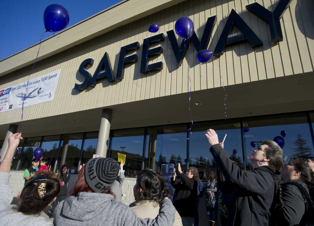 Safeway employees and well-wishers release balloons during a memorial for Brandon Cook, 30, on Monday. Police have charged Christopher Strawn, 32, for the crime and he is being held on $1 million bail.
