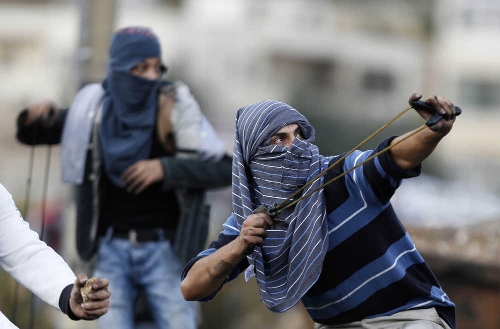 A Palestinian use a handmade slingshot to hurl a stone during clashes with Israeli troops near Ramallah, West Bank on Tuesday.