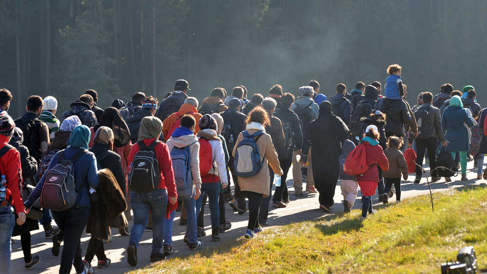 Migrants walk along a road after crossing the border between Austria and Germany on Wednesday.