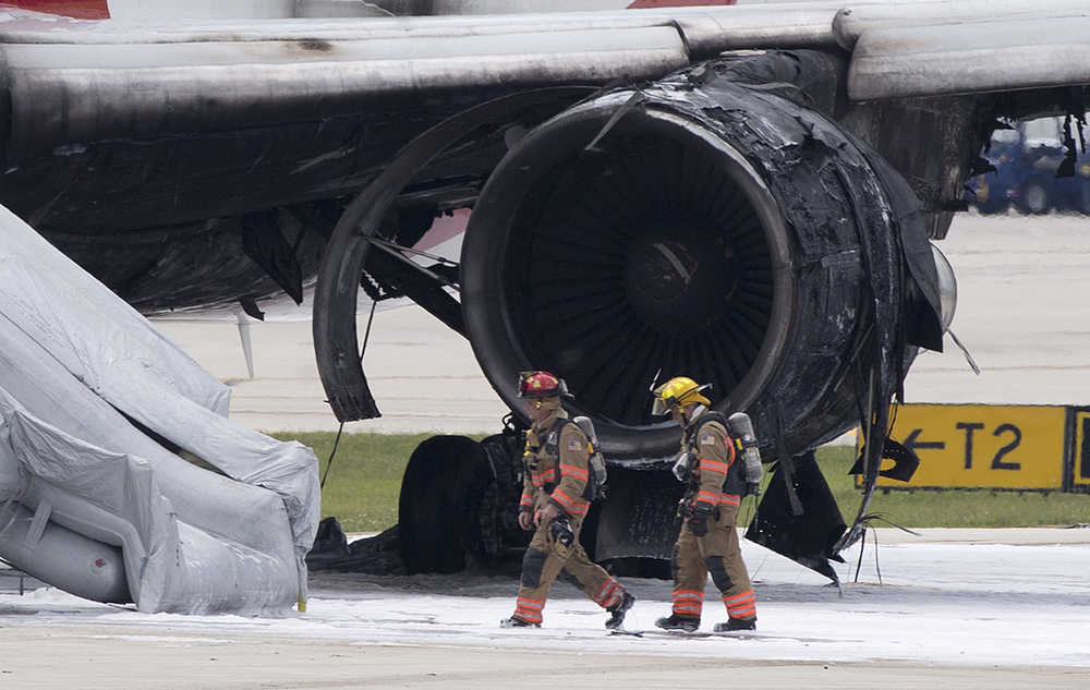 Firefighters walk past a burned out engine of a Dynamic Airways Boeing 767, Thursday, Oct. 29, 2015, at Fort Lauderdale/Hollywood International Airport in Dania Beach, Fla. The passenger plane's engine caught fire Thursday as it prepared for takeoff, and passengers had to quickly evacuate on the runway using emergency slides, officials said. The plane was headed to Caracas, Ven. (AP Photo/Wilfredo Lee)