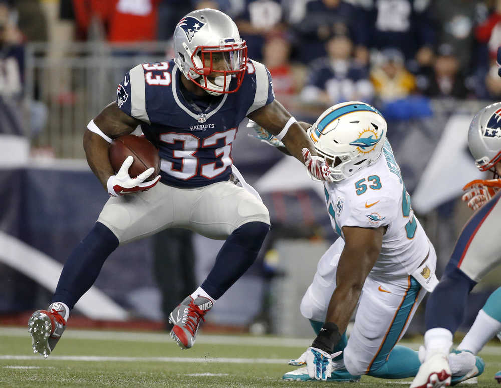 New England Patriots running back Dion Lewis (33) evades Miami Dolphins outside linebacker Jelani Jenkins (53) in the first half an NFL football game, Thursday, Oct. 29, 2015, in Foxborough, Mass. (AP Photo/Michael Dwyer)