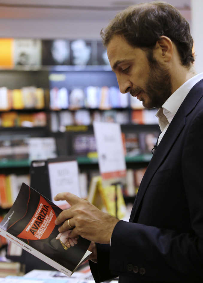 Italian journalist Emiliano Fittipaldi browses through his book titled " Avarice" in a Rome's bookstore on Tuesday.