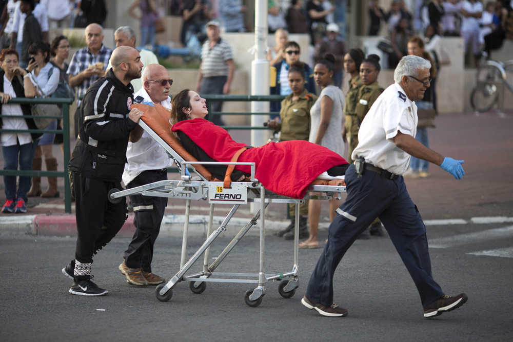 In this Monday photo, Israeli rescue personal evacuate a woman after a stabbing attack in Rishon Lezion, Israel.