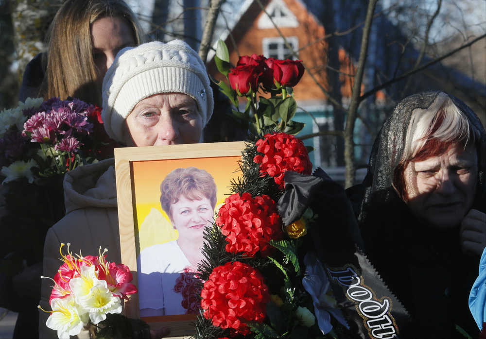 A woman holds a portrait of Nina Lushchenko, one of the victims of a plane crash,  during her funeral at a cemetery in the village of Sitnya, 80 km (about 50 miles) of Veliky Novgorod, Russia, Thursday, Nov. 5, 2015.  The first victim of Saturday's plane crash in Egypt was laid to rest on Thursday following a funeral service in a medieval church in the north Russian city of Veliky Novgorod.  Russia's Airbus 321-200 broke up over the Sinai Peninsula en route from the resort town of Sharm el-Sheikh to St. Petersburg, killing all 224 on board. (AP Photo/Dmitry Lovetsky)