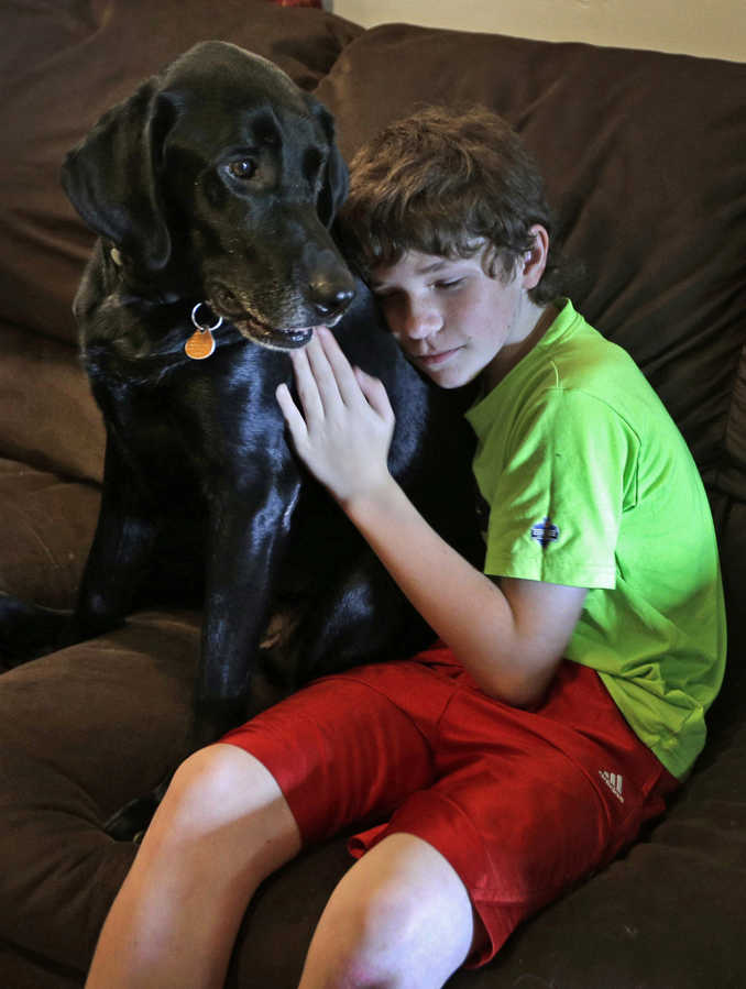 In this Sept. 8 photo, Jack Baker hugs his father's PTSD service dog, Honor, at his home in Clyde, N.C.