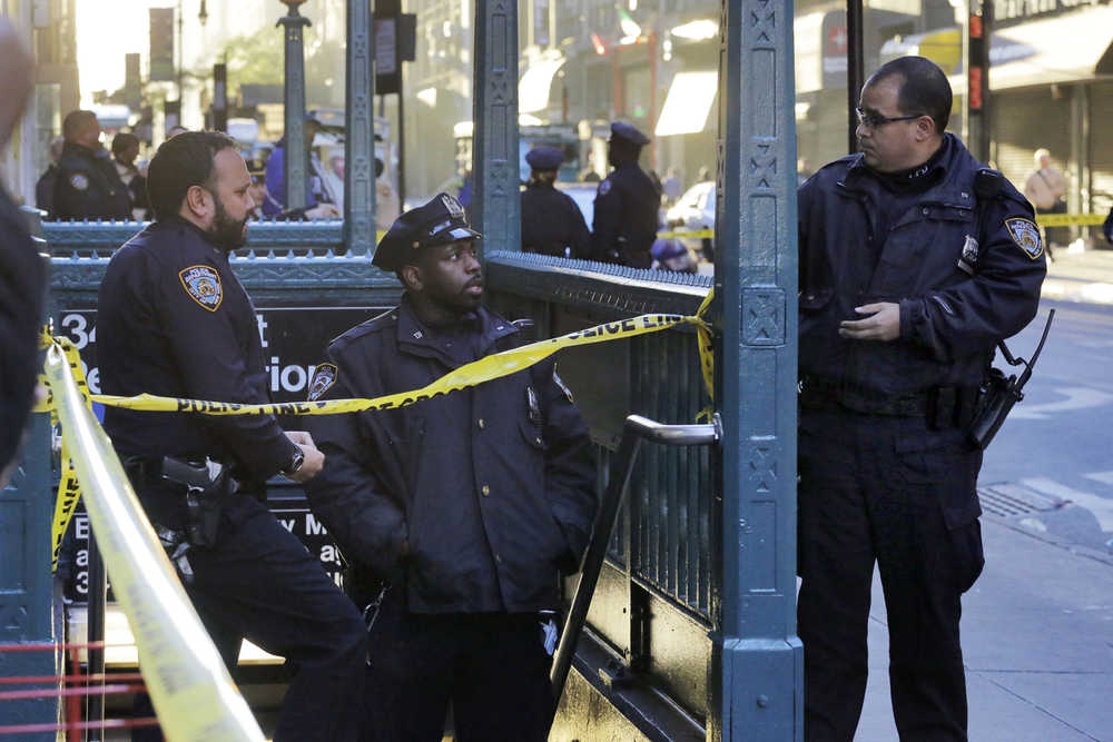 New York Police Department officers investigate a shooting at a subway station entrance at 35th Street and Eighth Avenue Monday in New York.