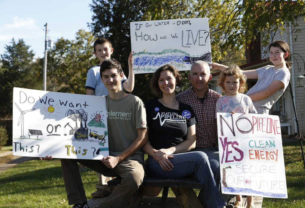 In this Oct. 20 photo, Carolyn Reilly, bottom center left, and her husband, Ian, bottom center right, and their children, clockwise from bottom left, Jonas, Elliot, Evelyn and Joy pose for a photo as they display their signs protesting the proposed natural gas pipeline at their home in Rocky Mount, Virginia.