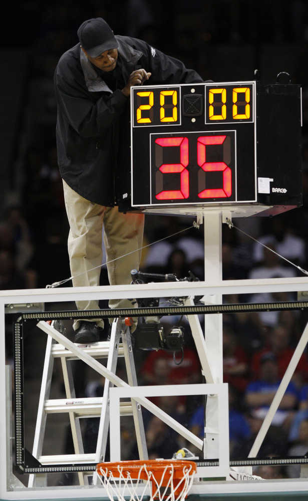 FILE - In this March 19, 2010, file photo, a technician adjusts a shot clock after it malfunctioned and delayed the start of the California against Louisville NCAA first-round college basketball game in Jacksonville, Fla. The NCAA has shaved 5 seconds off the shot clock, leaving teams 30 seconds to run their offense. Coaches don't expect dramatic changes, but practices have changed, communication and court awareness are more important than ever, and full-court pressure is getting a new look as a way to take advantage of the shorter time. (AP Photo/Steve Helber, File)