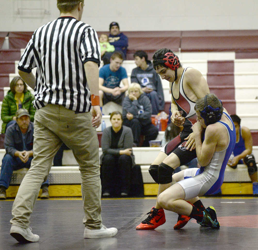 Juneau-Douglas senior Adam Murphy attempts to escape from Thunder Mountain freshman Connor Norman as Falcons senior Hunter Boyer officiates during the JDHS/TMHS senior appreciation dual meet on Friday at the JDHS gymnasium.