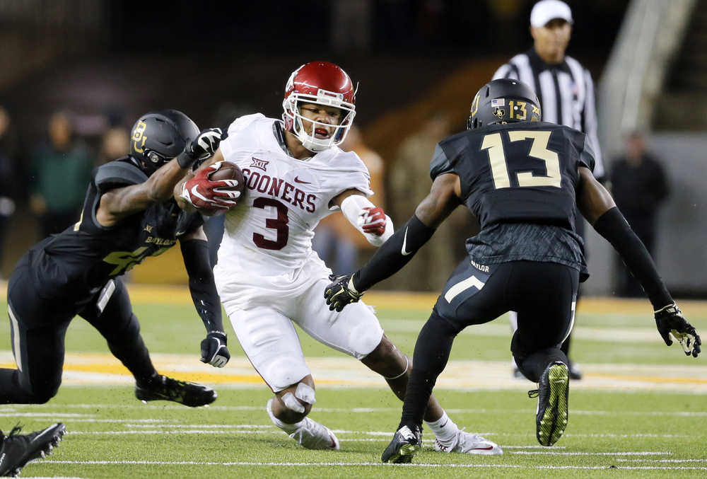 Oklahoma wide receiver Sterling Shepard (3) runs with the ball after making a catch as Baylor safety Calvin Hill, left, and safety Terrell Burt (13) attempt to make the stop in the second half of an NCAA college football game Saturday, Nov. 14, 2015, in Waco, Texas. Shepard had 14 catches for 177 yards and two touchdowns and No. 12 Oklahoma beat No. 4 Baylor 44-34 on Saturday night to end the Bears' 20-game home winning streak - and likely their playoff chances. (AP Photo/Tony Gutierrez)